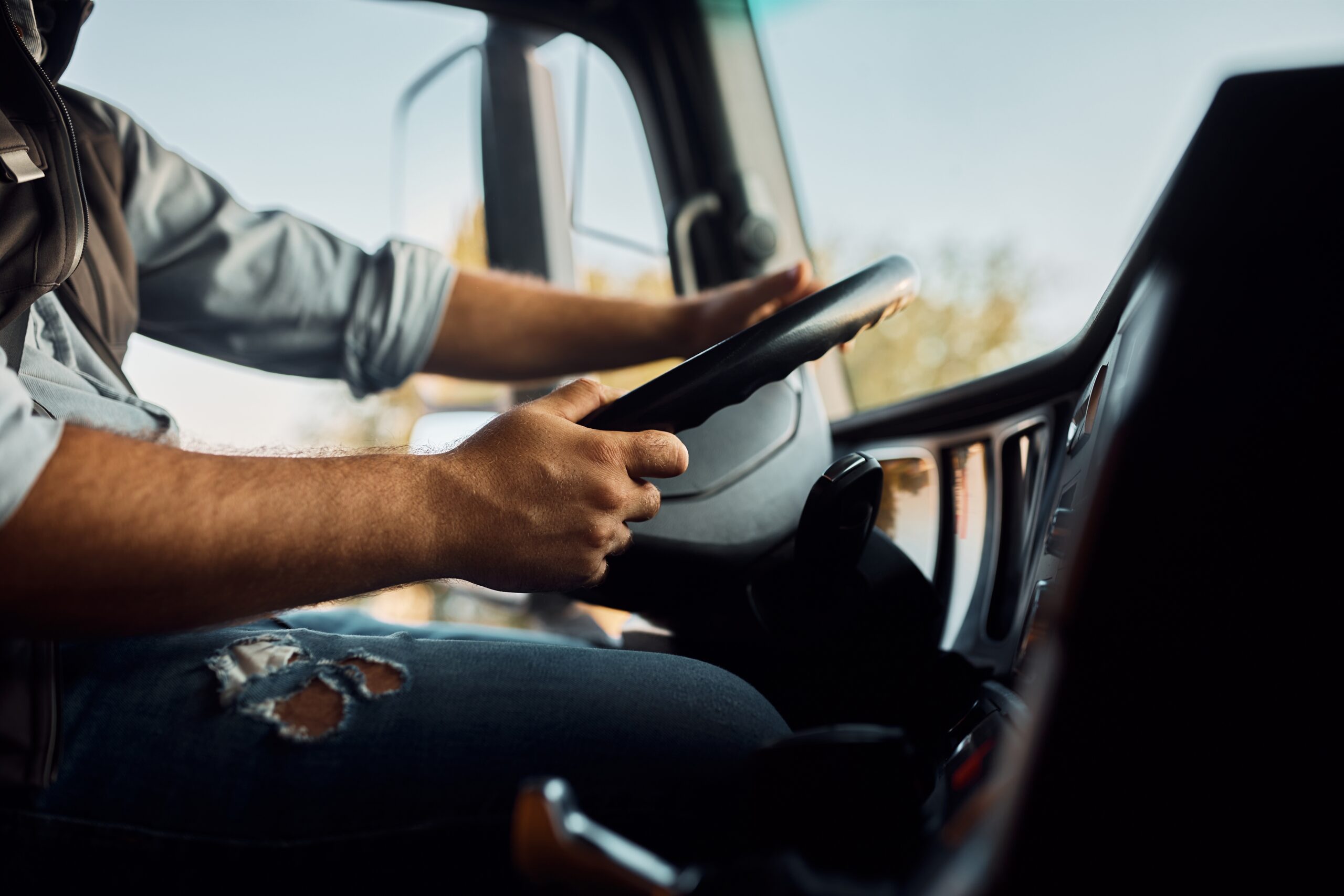 Close,Up,Of,Truck,Driver,Behind,The,Steering,Wheel,In