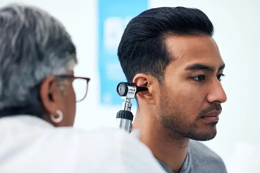 Doctor checking a mans ear with a medical device