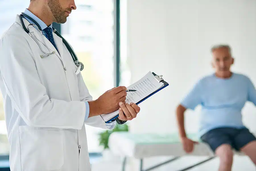 Male doctor holding pen and paper writing things down