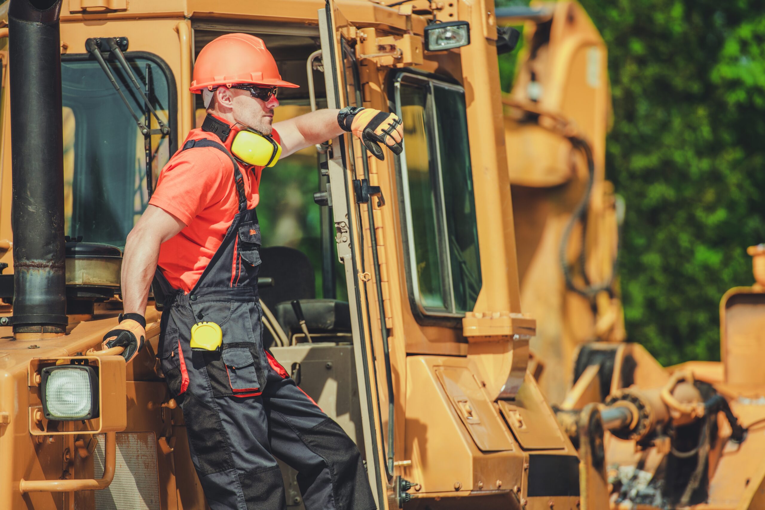 A,Man,In,Safety,Gear,Leans,On,Heavy,Machinery,At