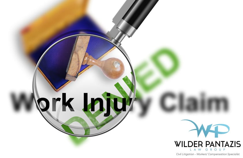 Magnifying glass focus on the words "Work Injury Claim" with other legal items in the background