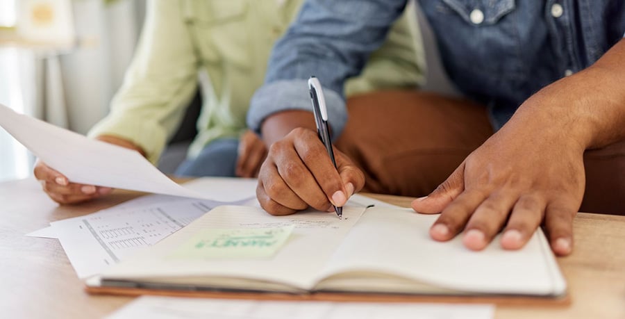 Paperwork being done by 2 people over a desk